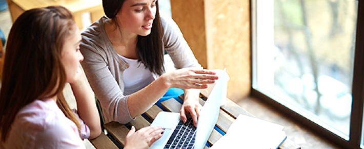 Zwei Studentinnen bereiten sich bei einem Kaffee auf ein Seminar vor.